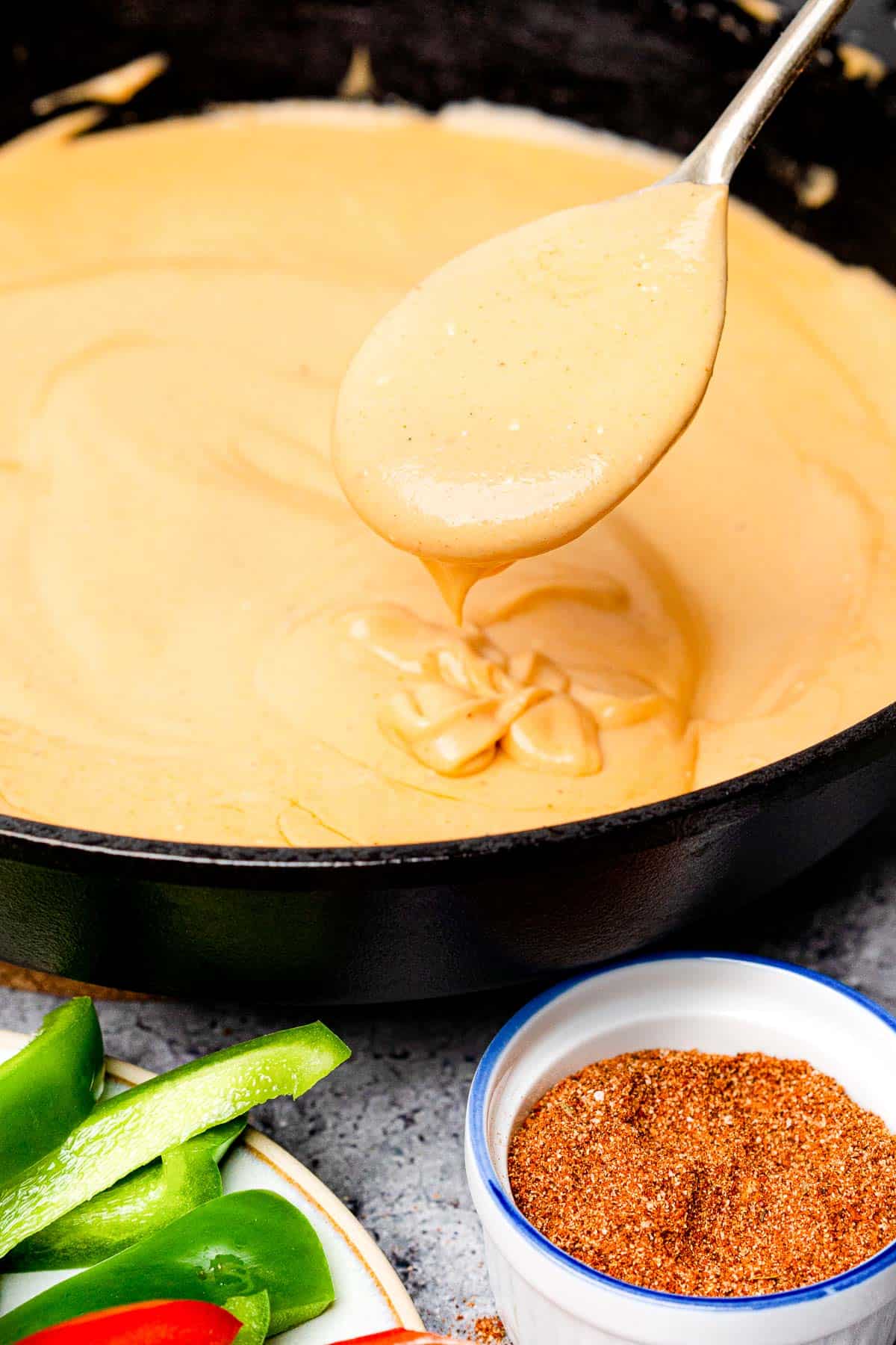 Keto Cheese Sauce in a cast iron skillet being scooped up with a spoon
