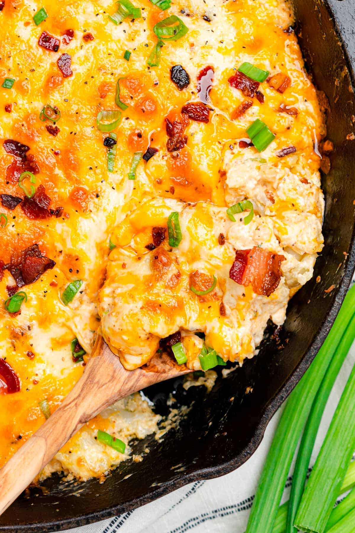 Keto Cauliflower Casserole closeup with a spoon scooping into the casserole to remove a serving.