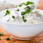 Is Cream Cheese Keto? We find out! This image is a white bowl containing cream cheese topped with chives.