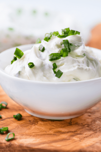 Is Cream Cheese Keto? We find out! This image is a white bowl containing cream cheese topped with chives.