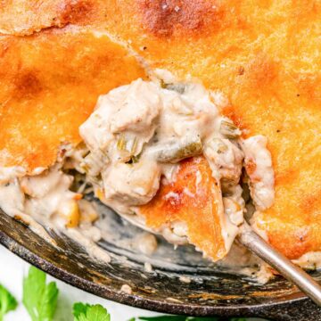 Keto Chicken Pot Pie in a cast iron skillet with a spoon taking a serving out