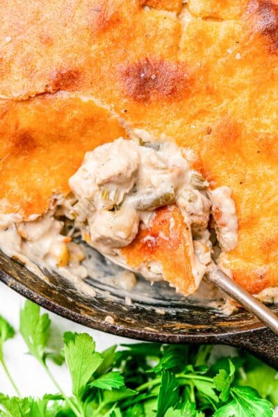 Keto Chicken Pot Pie in a cast iron skillet with a spoon taking a serving out