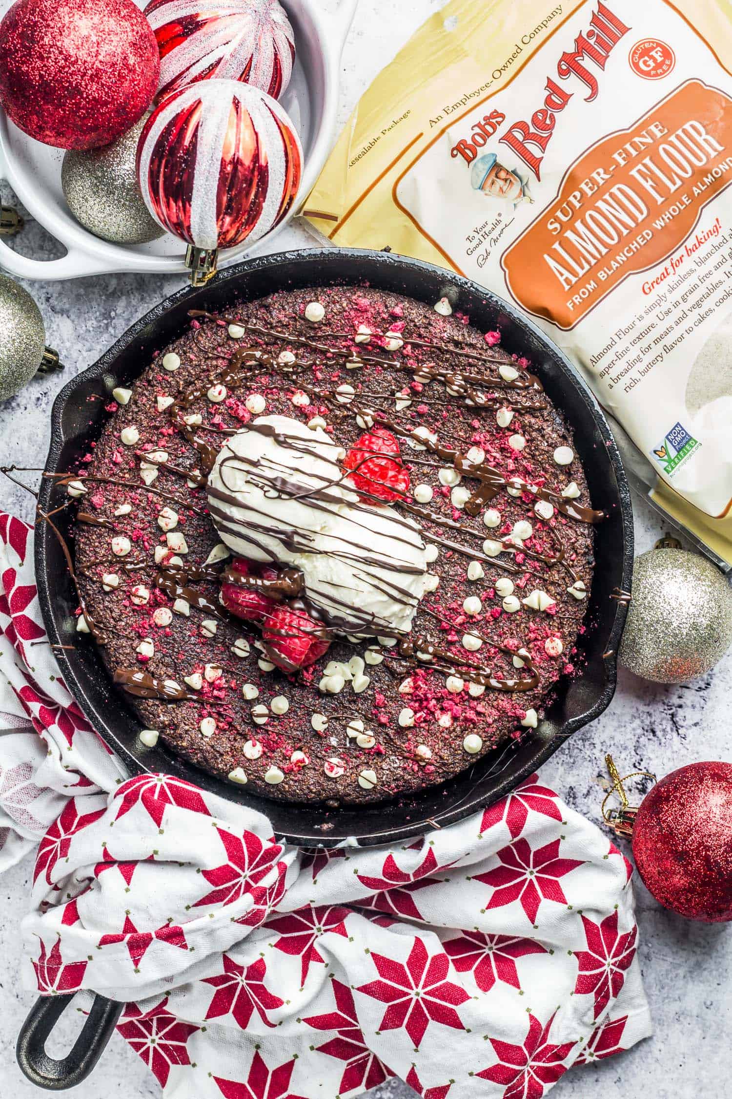 Keto Red Velvet Skillet Cookie on a backdrop with red globe ornaments scattered around