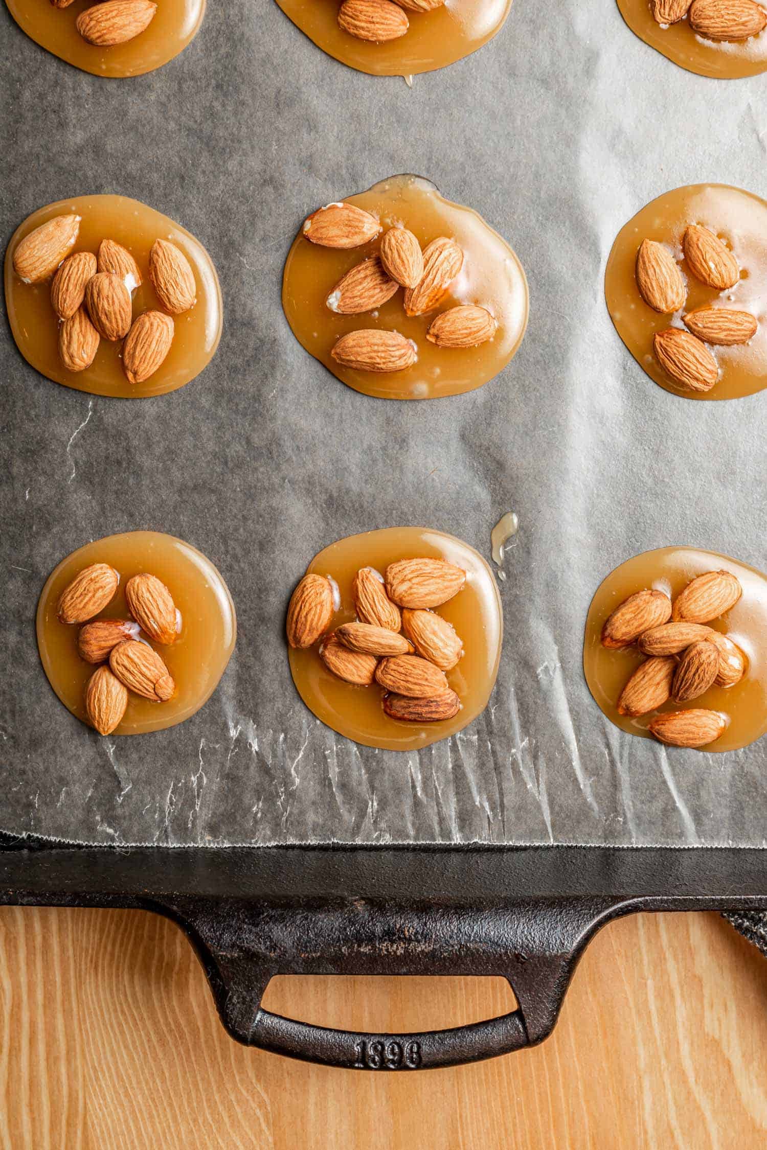 caramel almond disks on a lined baking sheet