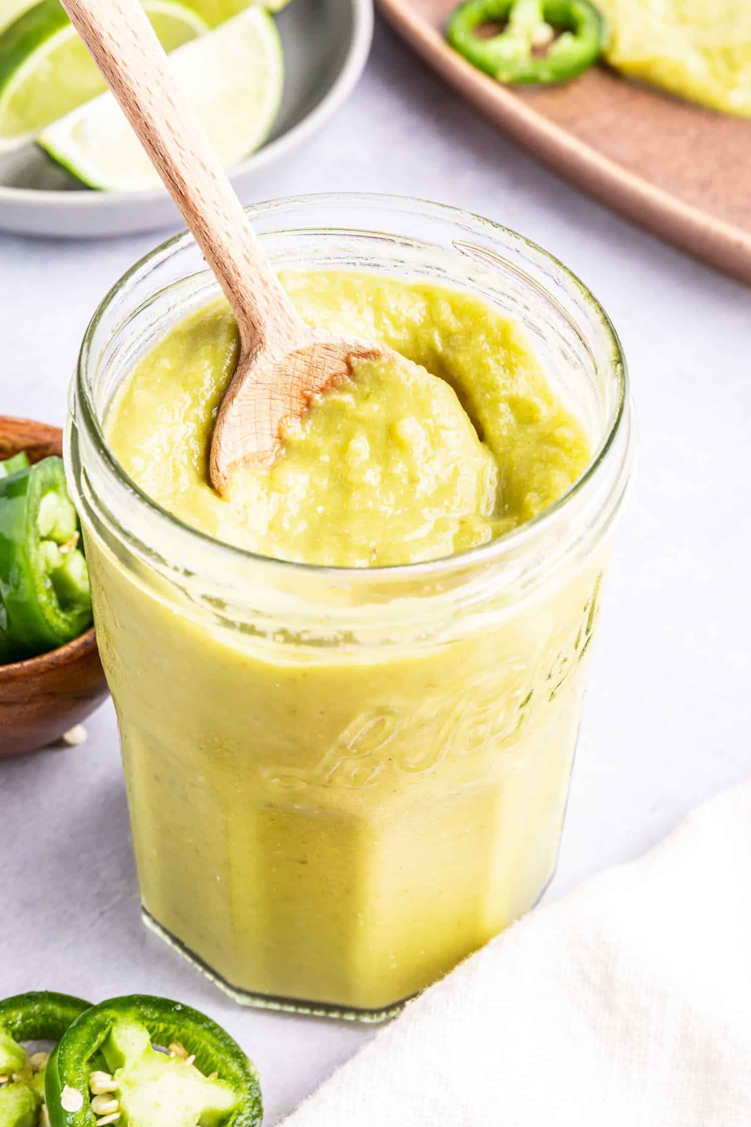 Creamy Jalapeño Sauce in a glass jar with a spoon in it