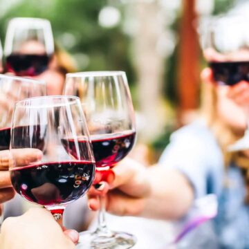 a group of people eating outside while raising their wine glasses to a toast