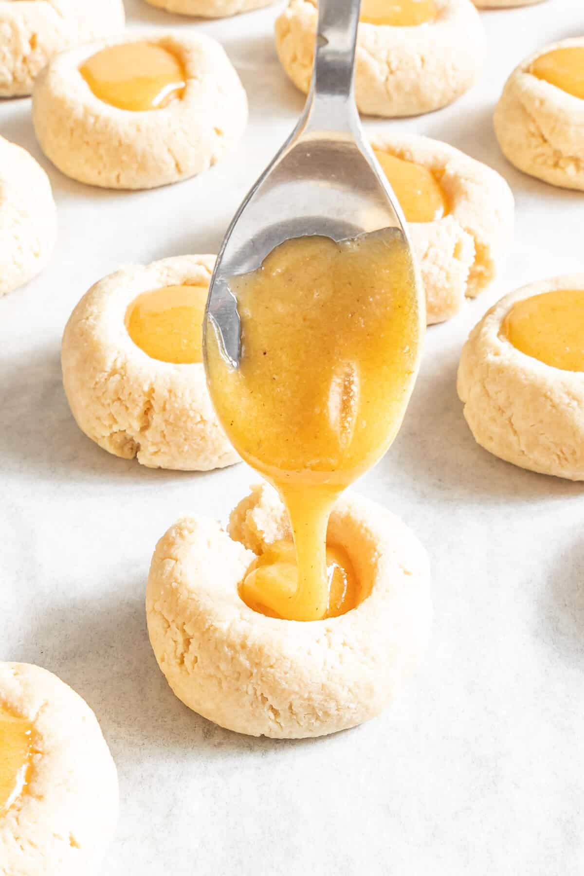 spooning caramel into the center of the thumbprint cookies