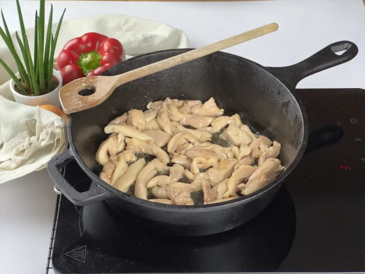Sliced chicken thigh cooked in a cast iron pan.
