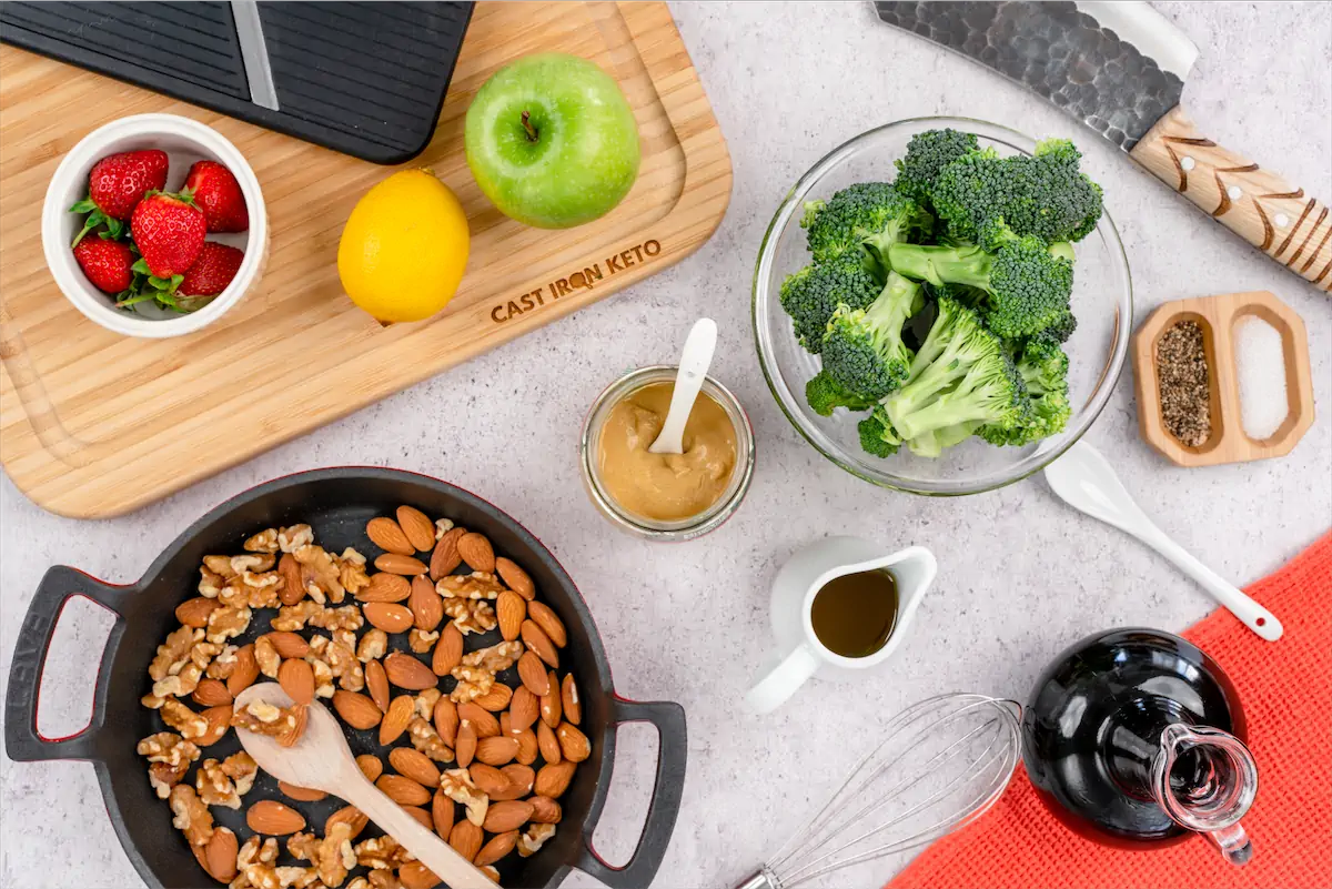 Ingredients like broccoli, almonds, apple, lime, strawberries, blasamic vinegar on kitchen table,
