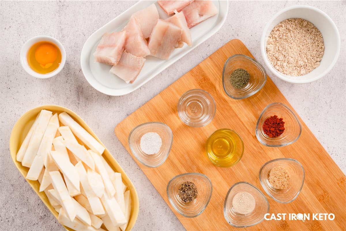 a wooden cutting board topped with bowls of ingredient for our keto-friendly fish and chip recipe