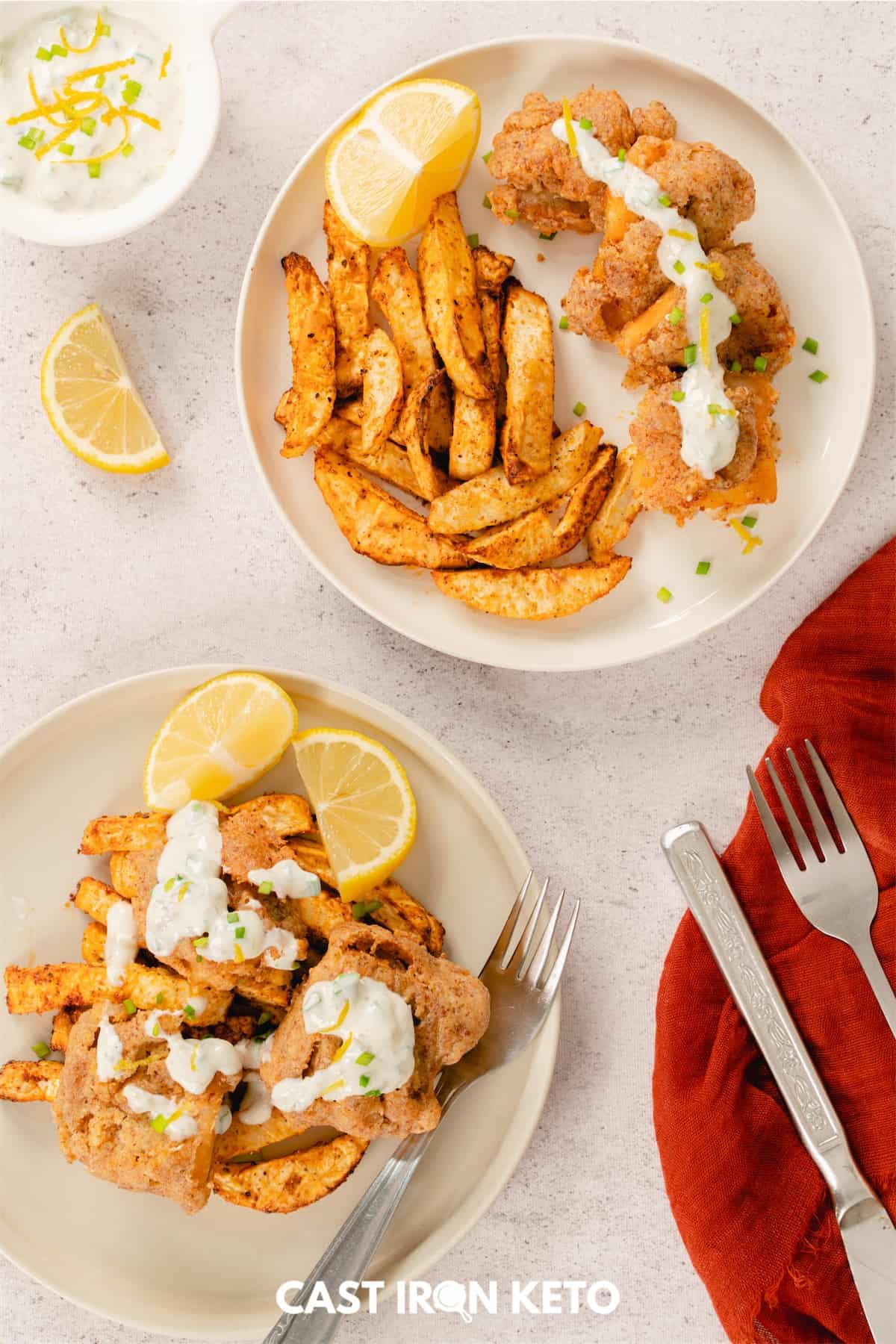 two plates of keto-friendly fish and chips on a table with a fork and knife.