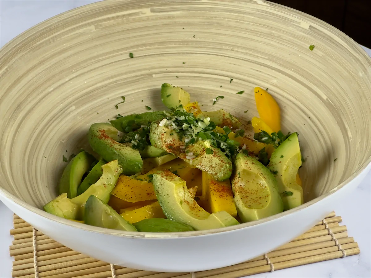 Sliced mangoes, avocados and other ingredients in a bowl.