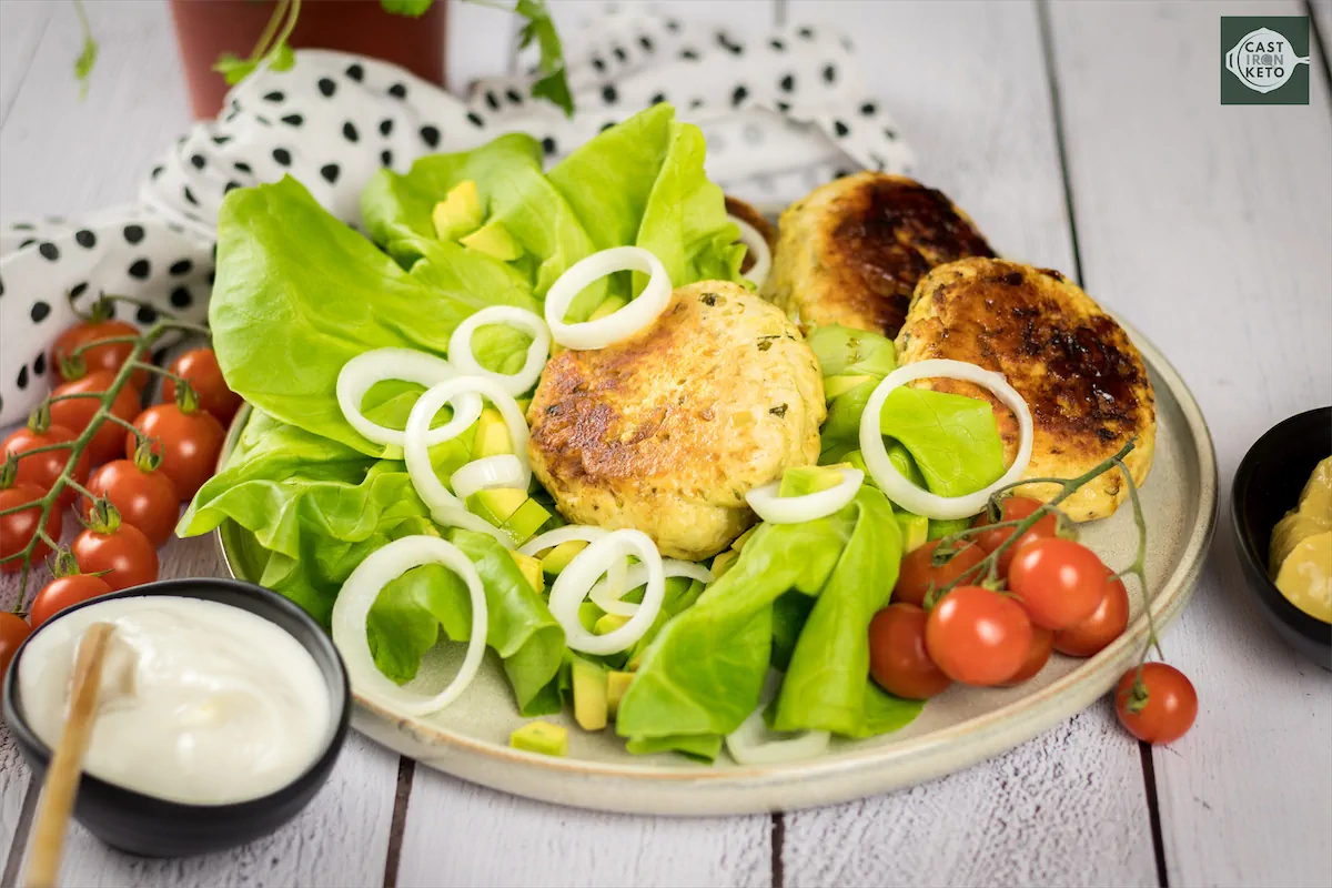 Keto Turkey Burgers served on a plate garnished with lettuce, onions, and cherry tomatoes.