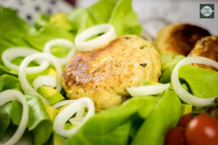 Aesthetic arrangement of low-carb turkey burgers on a lettuce leaf, with a sprinkle of onions and cherry tomatoes adding color.