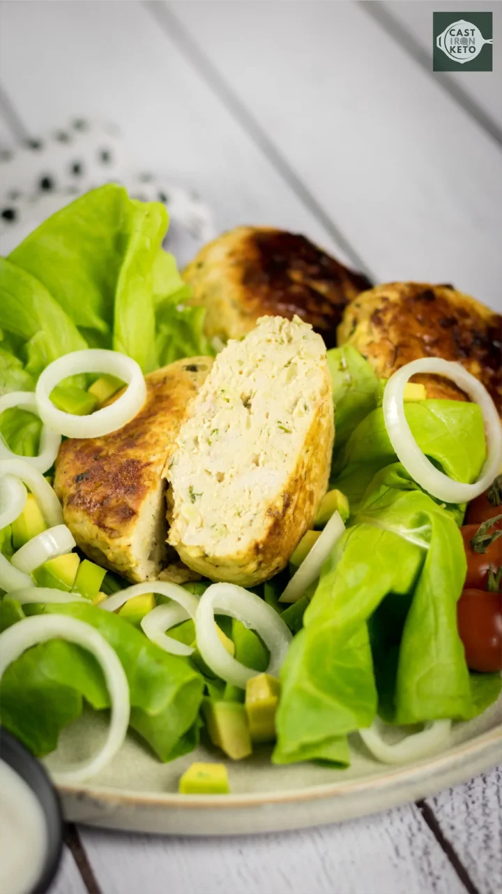 No-bun keto burger cut into half and placed on lettuce leaves.