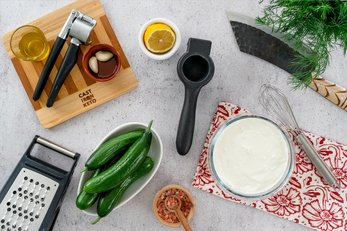 A stunning presentation of homemade keto tzatziki with olives, displayed on a white plate and kitchen tools