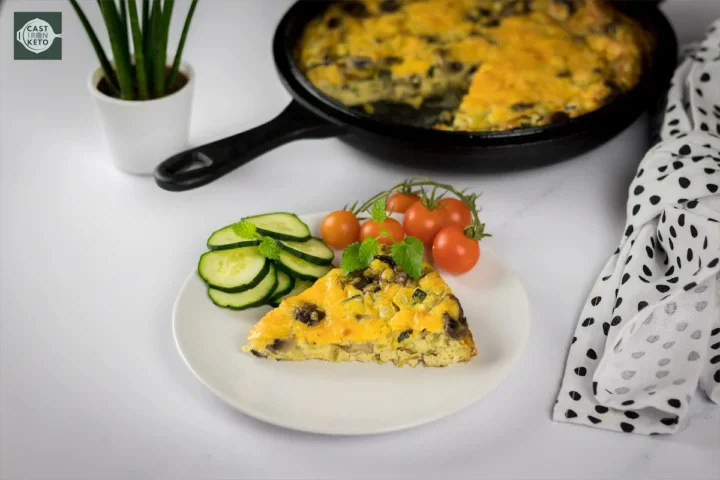 Frittata served on a white plate with a side of cucumber slices and a cluster of ripe cherry tomatoes.