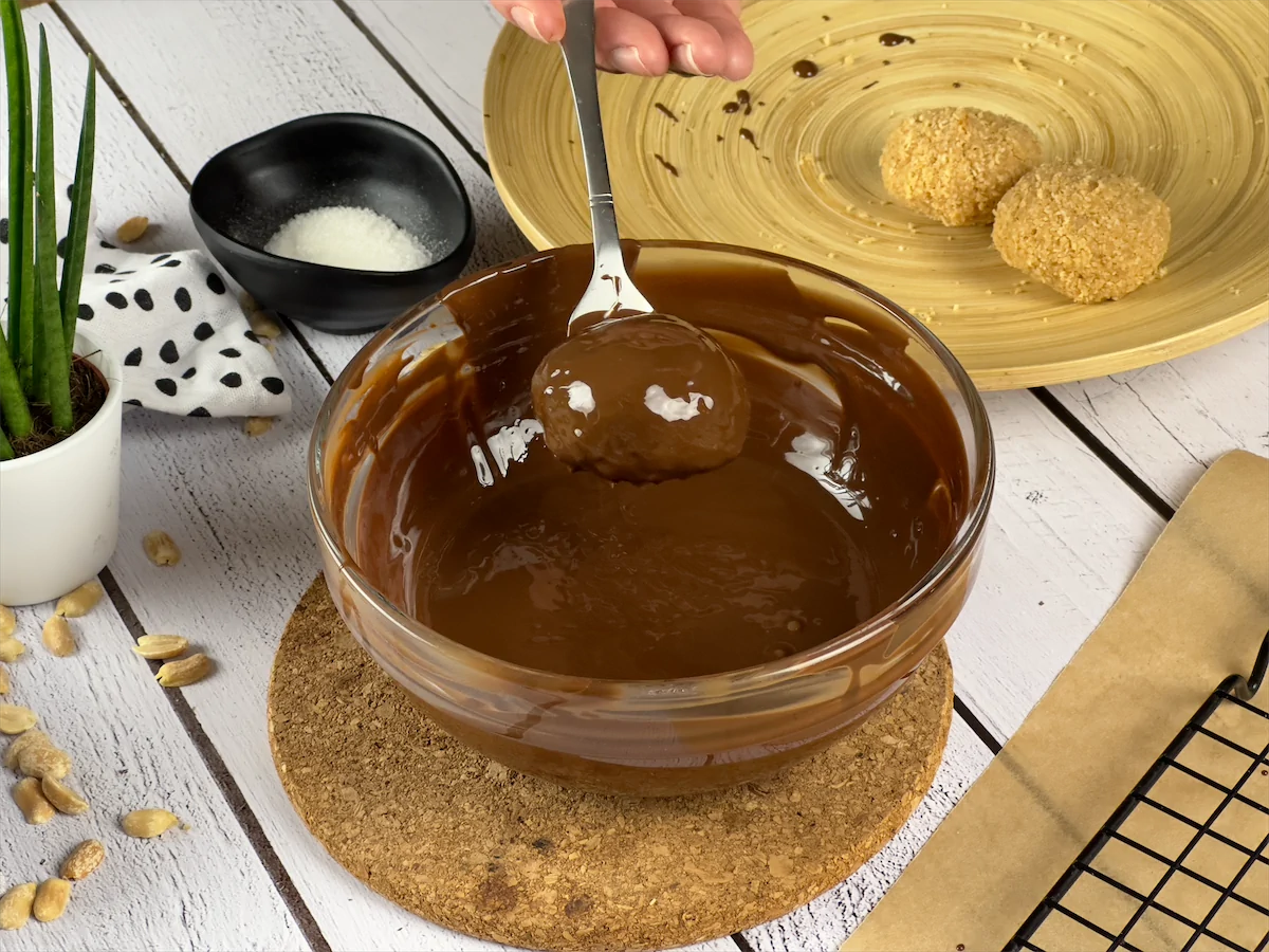 Cookie being dipped into the melted chocolate.