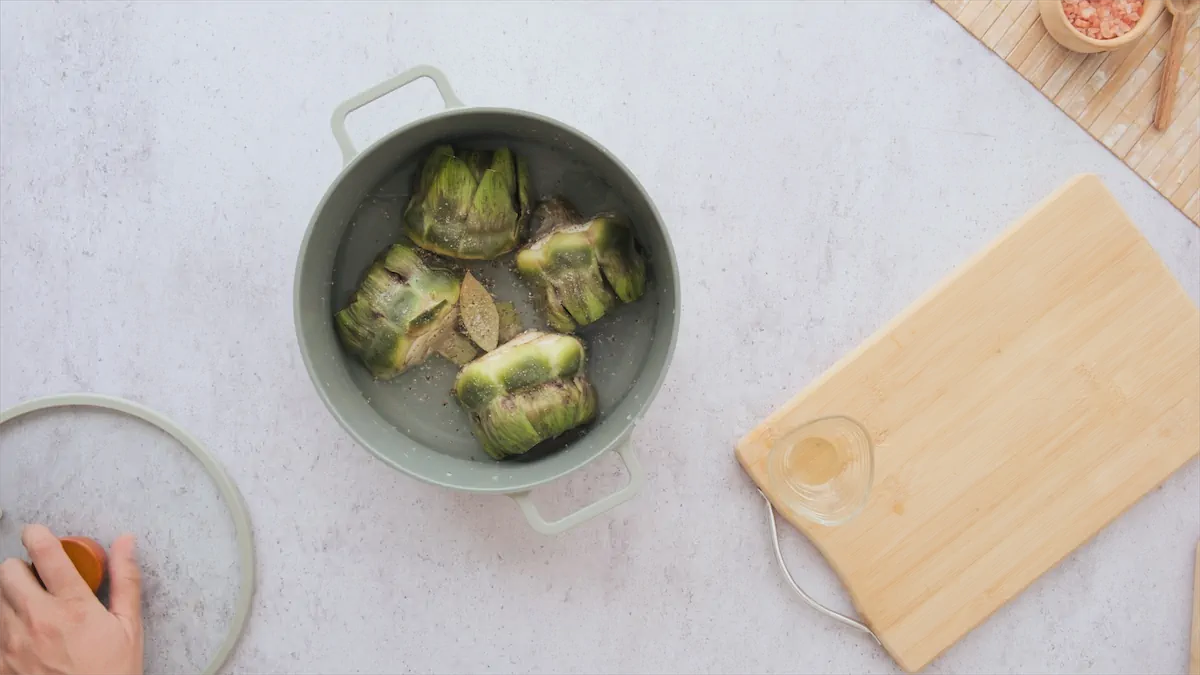 Cooking artichokes, bay leaf, and salt in hot water.
