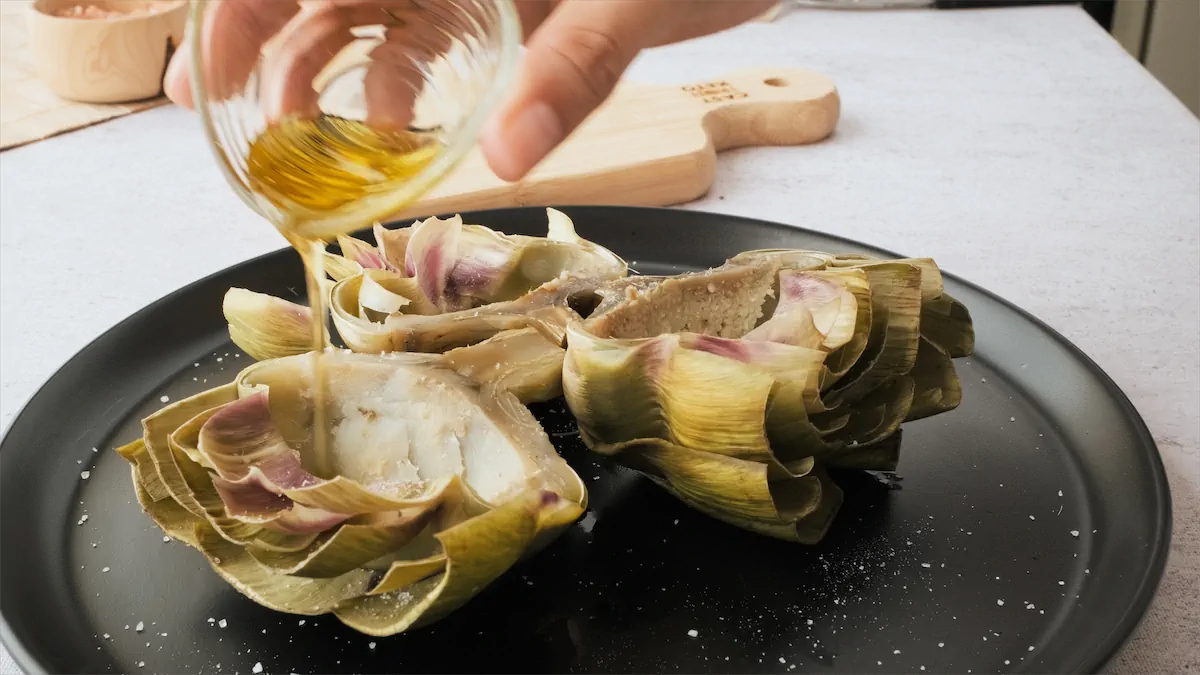 Drizzling some olive oil over the artichokes.