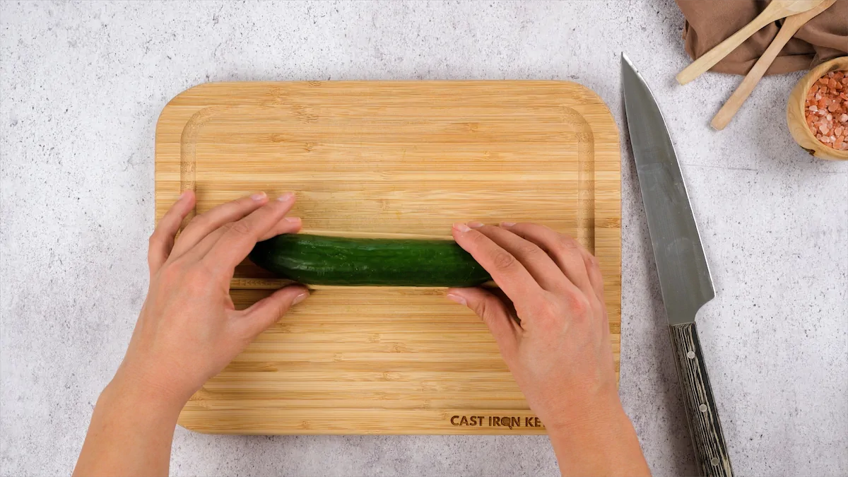 Placing a cucumber between chop sticks on a chopping board.