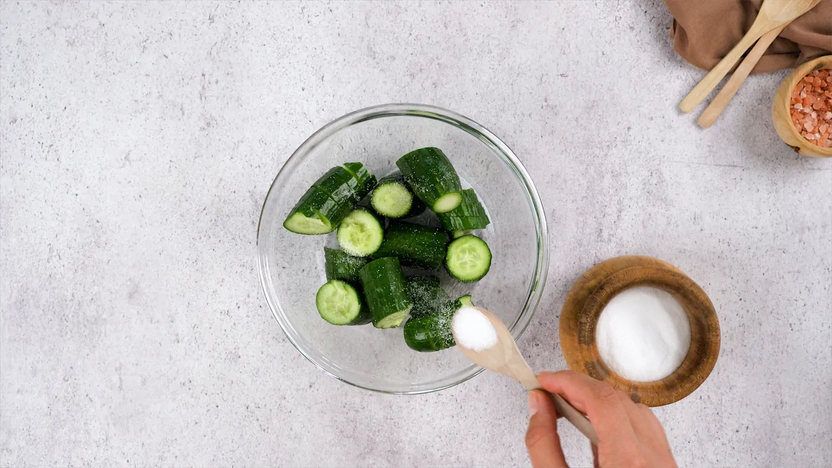 Sprinkling salt on chopped cucumbers in a bowl.