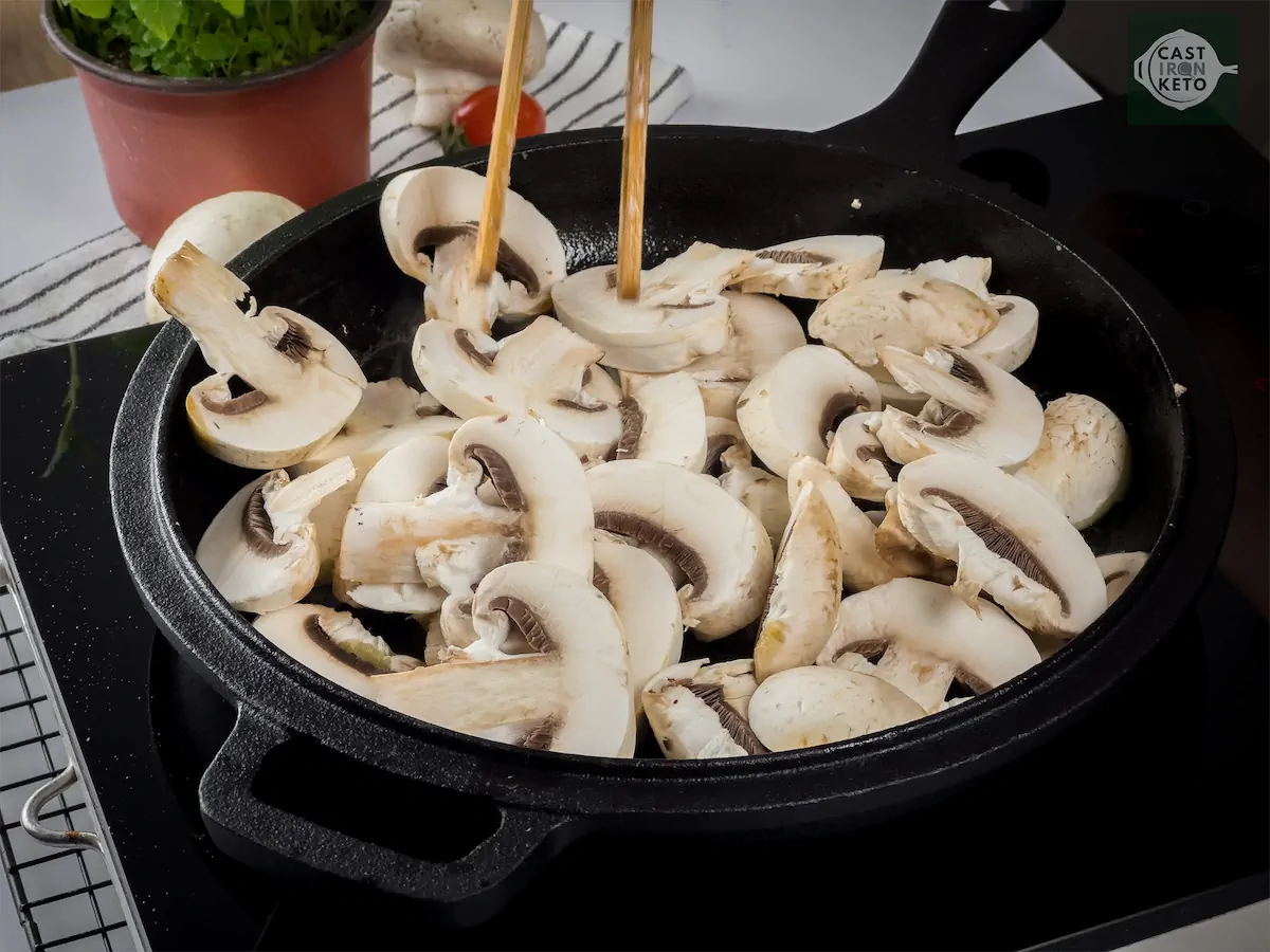 Cooking chopped mushrooms in a cast iron pan.