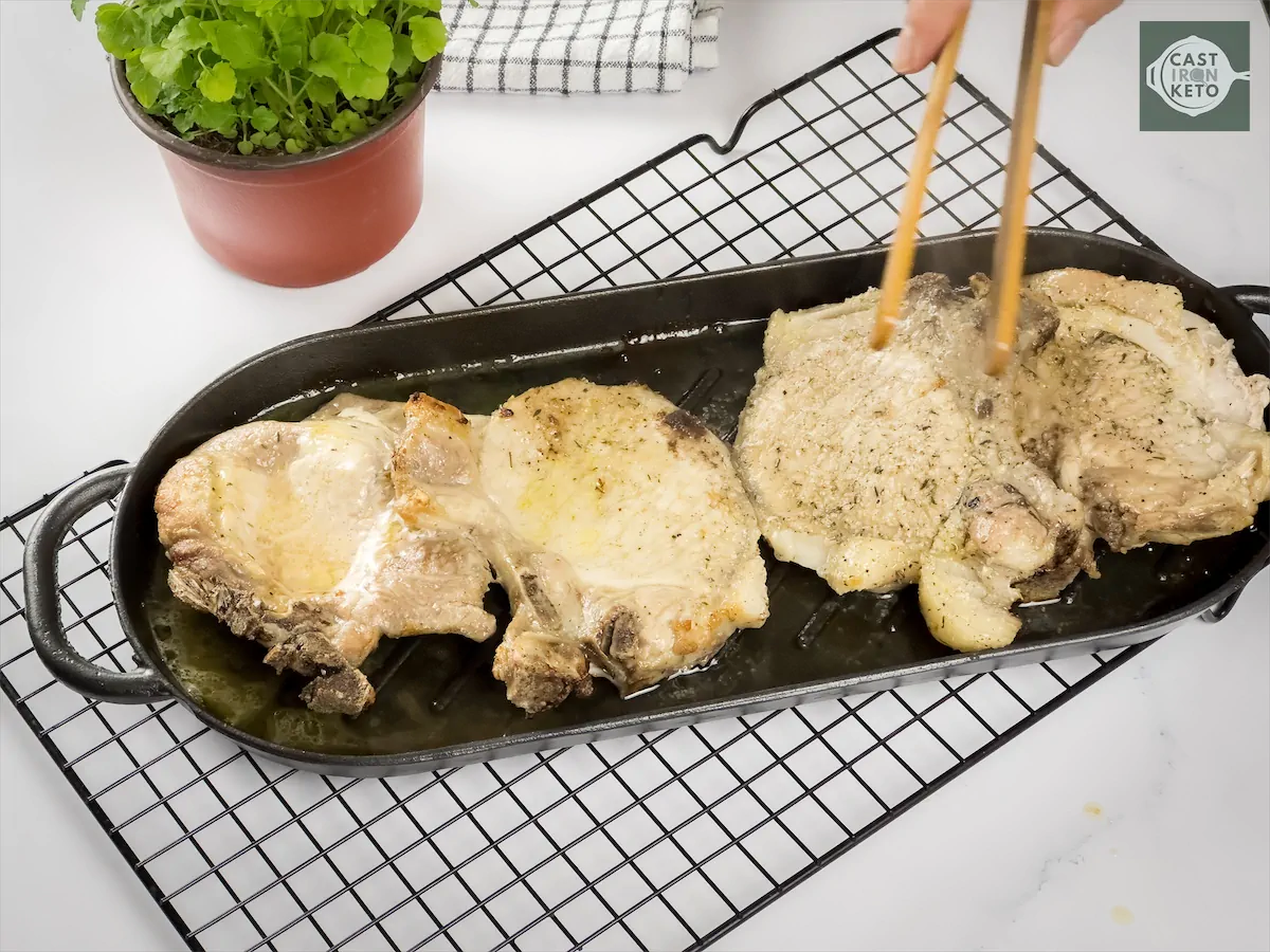 Baked pork chops on a cast iron baking dish.