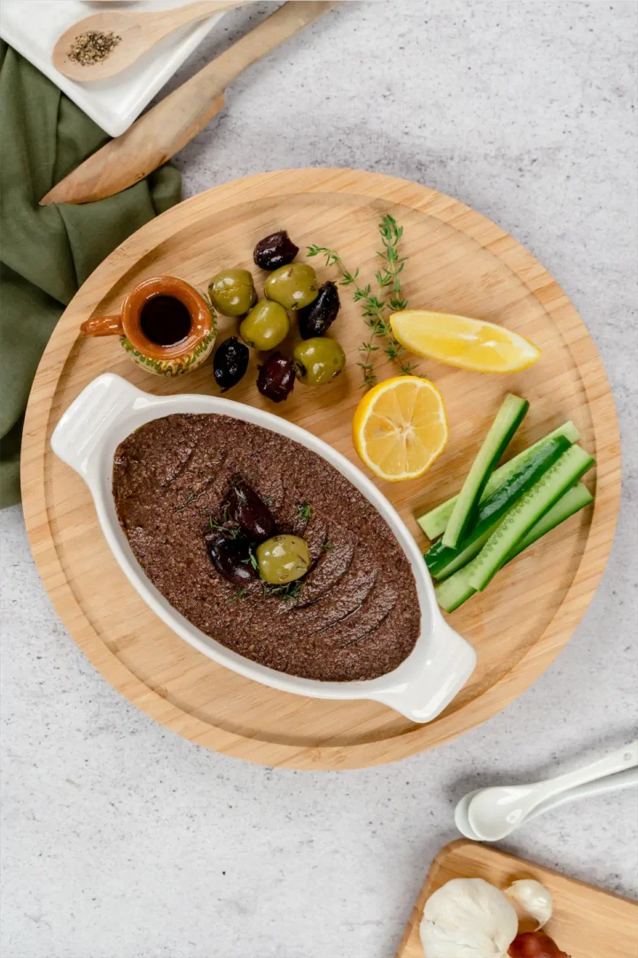 Keto Olive Tapenade served on kitchen bowl with some veggies.