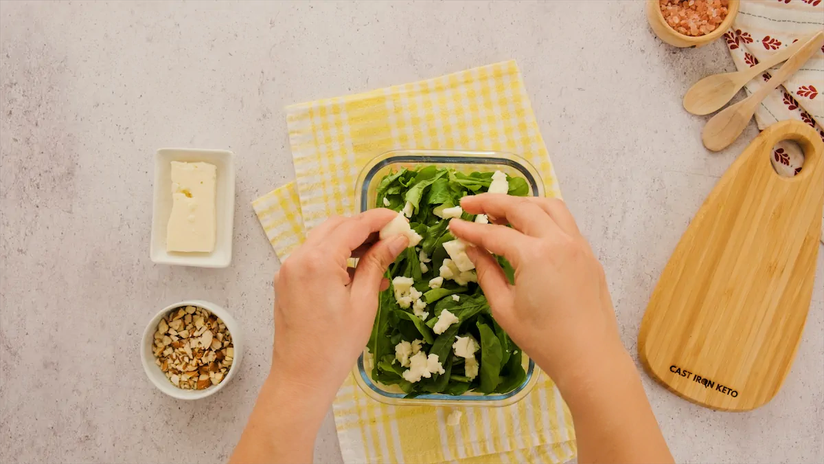 Adding feta cheese to the salad ingredients.