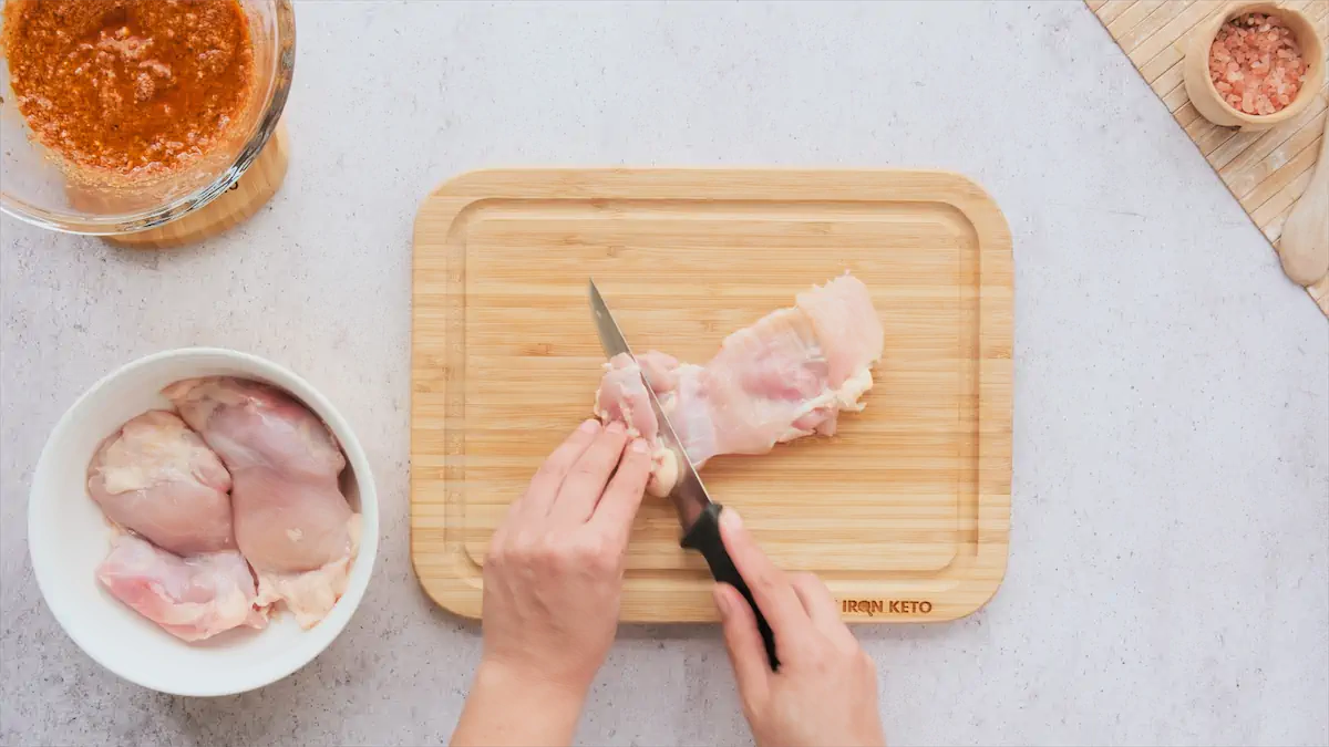 Cutting the boneless skinless chicken thighs into pieces.