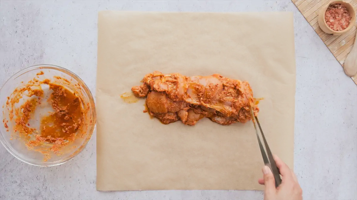 Placing the chicken coated with the marinade in a wrapping paper.