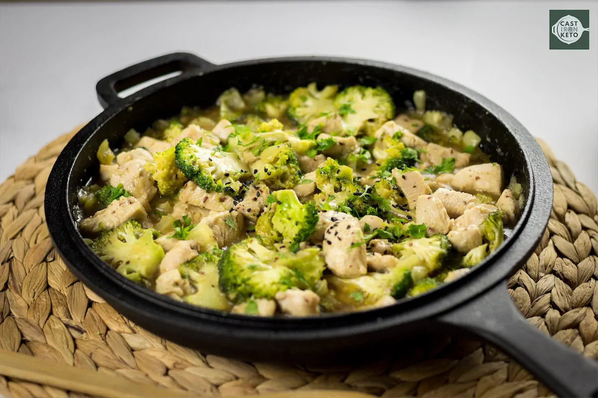 Keto chicken stir fry cooked in a cast iron skillet, featuring chunks of chicken and broccoli.