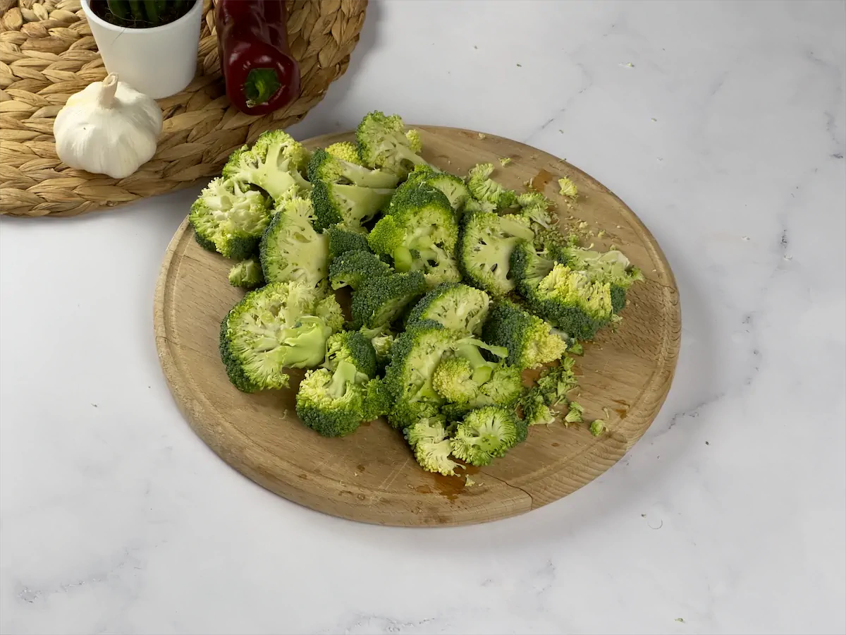 Chunks of chopped broccoli on a chopping board.