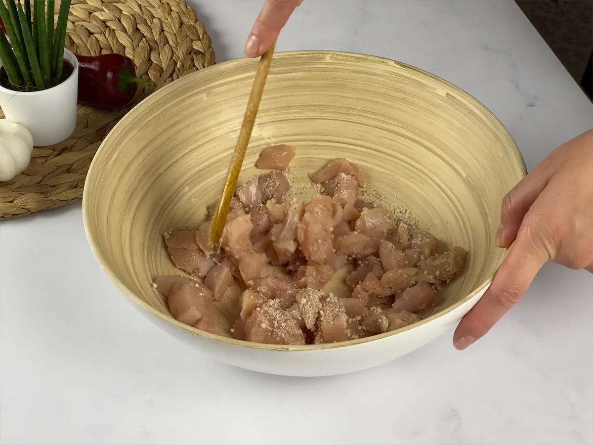Mixing diced chicken and almond flour in a large bowl.