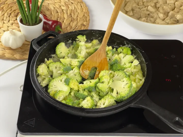 Cooking broccoli and other veggies in a cast iron pan.