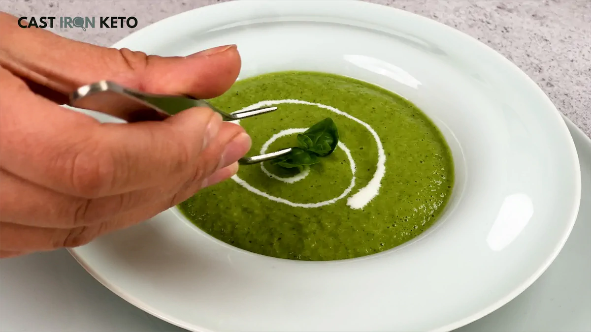 Garnishing a bowl of Keto Cucumber Gazpacho Recipe with fresh basil.