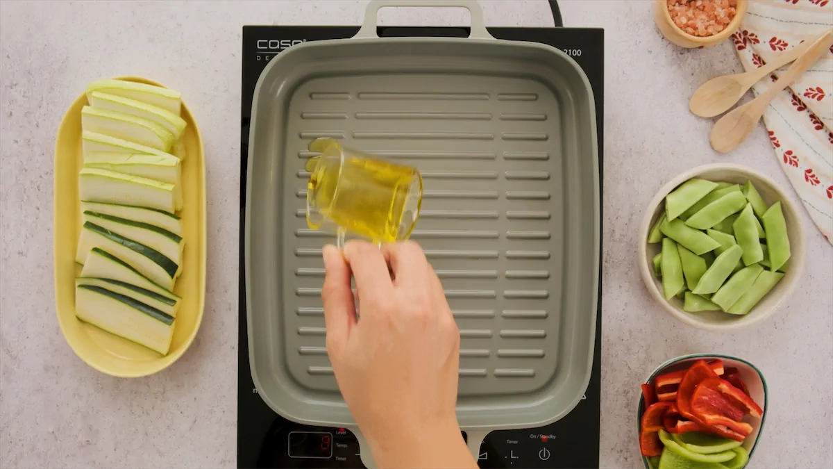 Olive oil being poured in a grill pan.