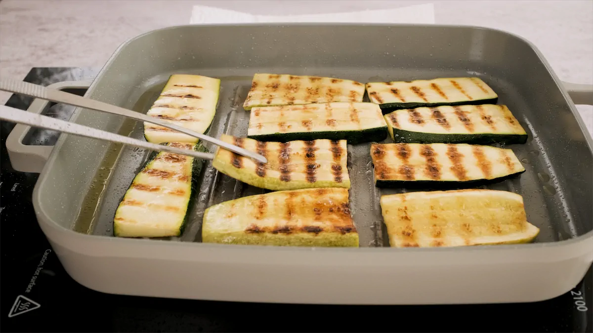 Grilling sliced zucchini and squash in a grill pan.