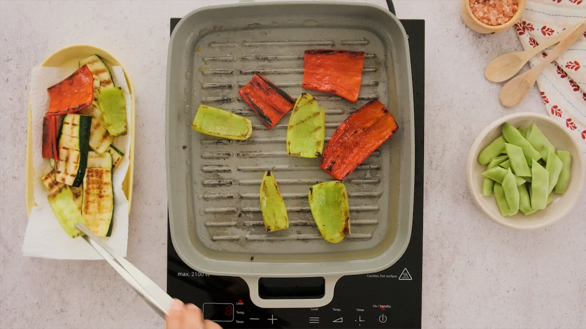Grilling sliced red and yellow bell peppers in a grill pan.