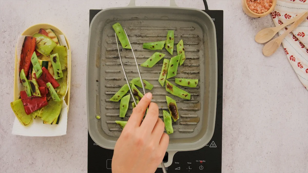 Grilling chopped green flat beans in a grill pan.