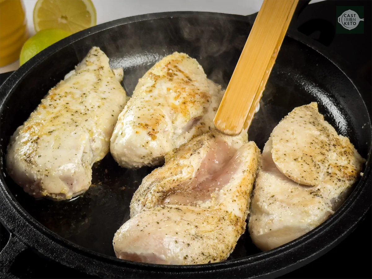 Chicken breasts being browned in a cast iron pan.