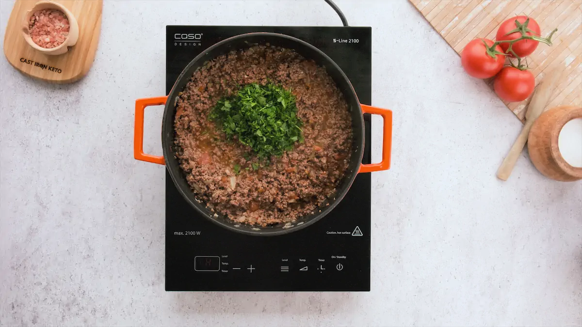 Cooking ground beef and other ingredients in a cast iron skillet.