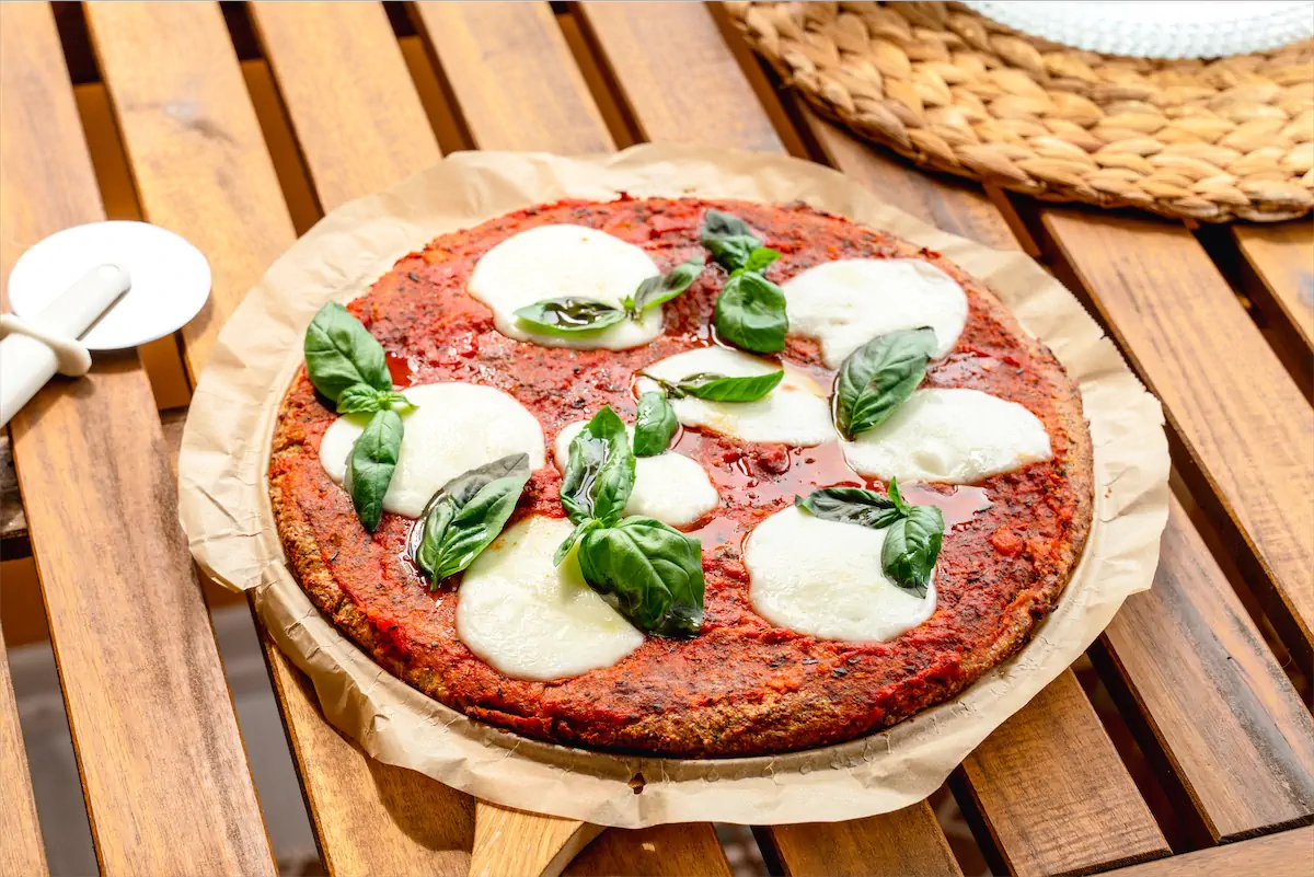 Low carb pizza topped with mozzarella cheese and basil leaves.