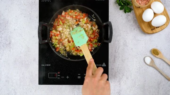 Sautéing the veggies in skillet with a spatula.