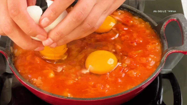 Cracking and adding eggs to the cast iron skillet.
