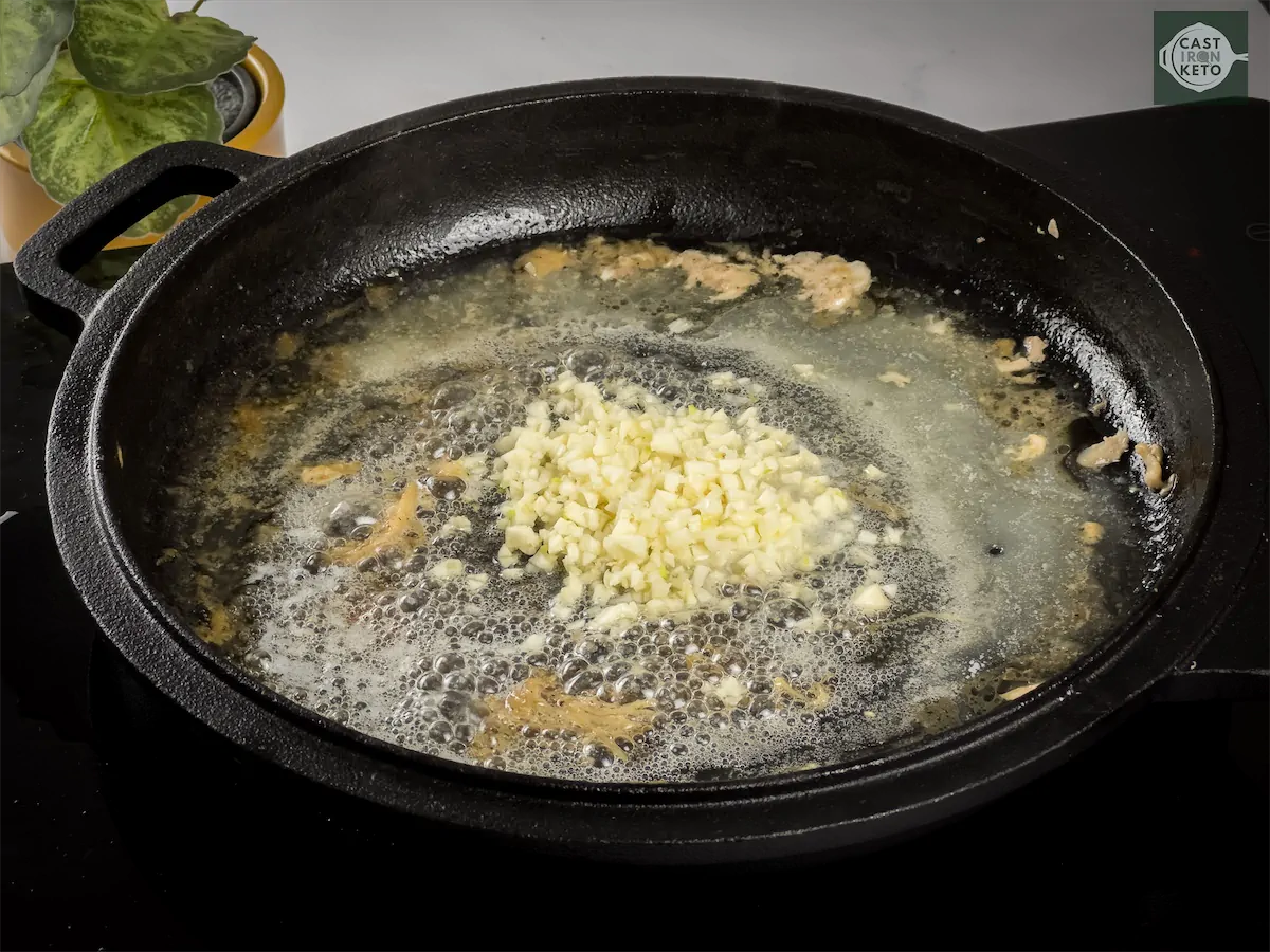 Cooking garlic and Italian seasoning in melted butter in a cast iron dish.