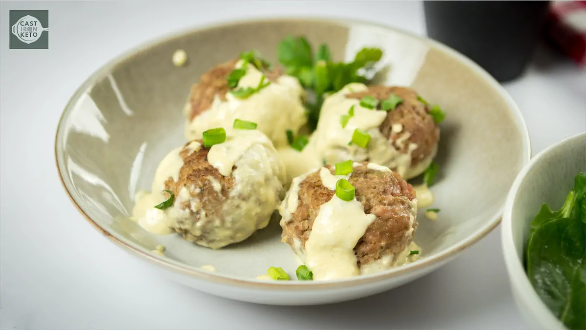 Herb-garnished meatballs in creamy sauce.