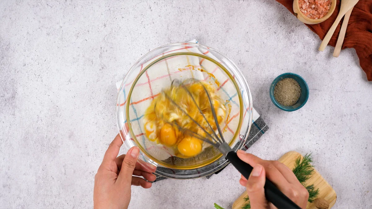 Whisking eggs with a whisker in a mixing bowl.