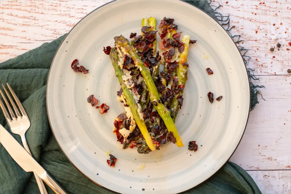 Roasted asparagus and bacon crumbs served on a plate.
